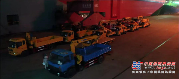 一艘万吨巨轮缓缓驶来	停泊靠岸	灯火通明的港口瞬间热闹起来	数十台在灯火映照下的徐工设备	泛出暖暖的黄晕色